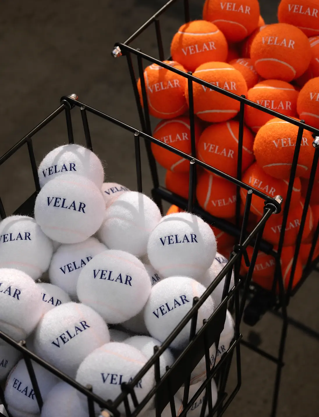 Baskets of white and orange tennis balls bearing the VELAR name