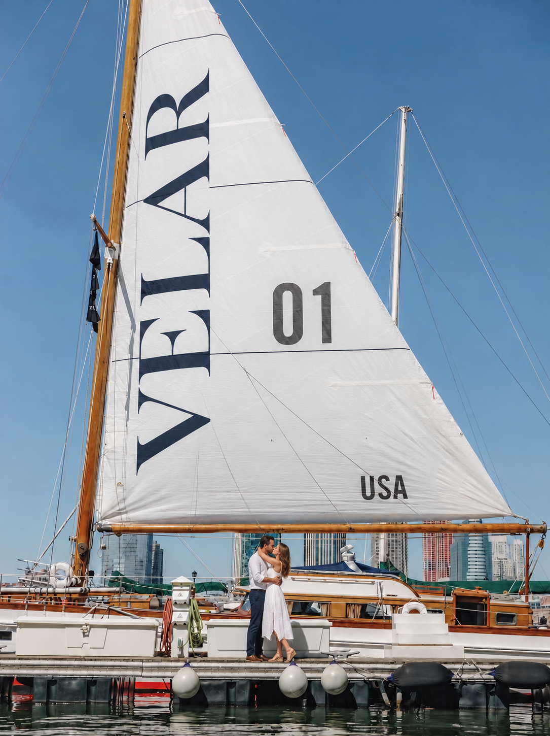 Classic sailboat with a VELAR 01 sail moored in the harbor, a couple on the dock
